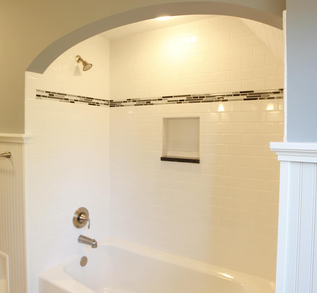 Bathtub surround with subway tile and contrasting accent tile